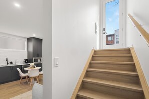 Eine moderne Küche mit dunklen Schränken, einer weißen Arbeitsplatte und einem Essbereich mit kleinem Tisch und Stühlen.