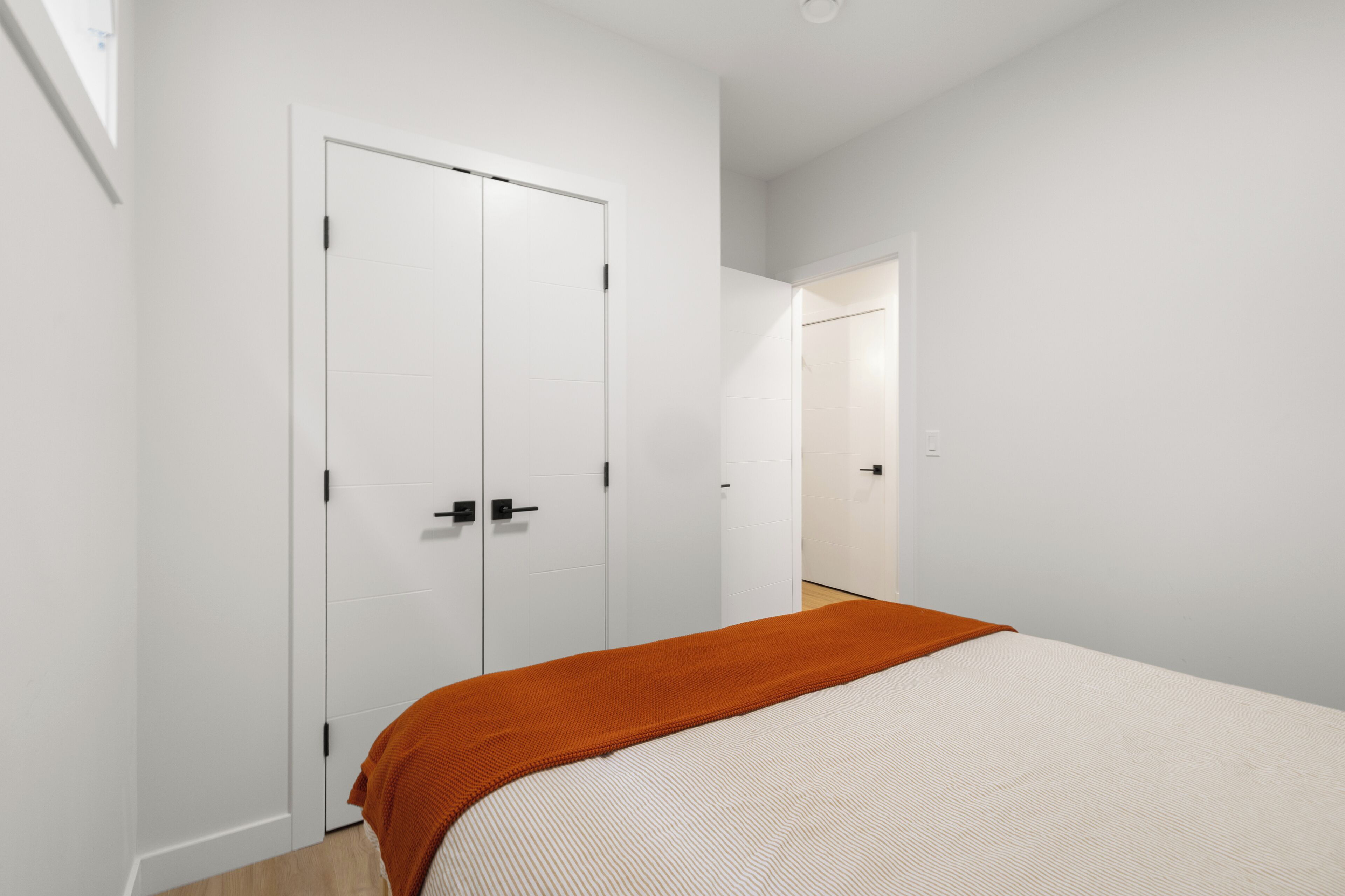 Une chambre à coucher comprenant un lit, une armoire et une porte donnant sur une autre pièce.