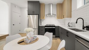 Una cocina moderna con un refrigerador de acero inoxidable, horno empotrado y cafetera.