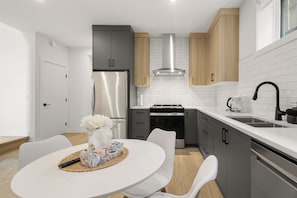 Eine moderne Küche mit einem Edelstahl-Kühlschrank, einem eingebauten Backofen und einer Kaffeemaschine.