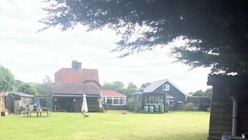 A grassy yard with a house, a garage, and a wooden structure.