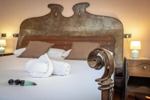 Een net opgemaakt bed met kussens, een opgerolde handdoek en een flesje lotion.