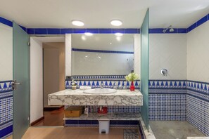 Een badkamer met een wit wastafel, blauw-wit betegelde muren, een spiegel en een douche.