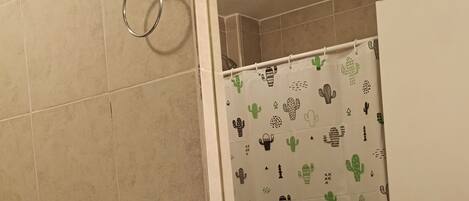 A bathroom with a toilet, sink, and shower curtain with cactus patterns.