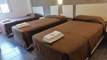 Habitación de hotel con dos camas individuales, cada una con cubrecama marrón y toallas blancas.