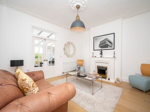 A living room with a sofa, coffee table, fireplace, and a large mirror. - Stylish House - 25mins London Bridge train journey - Pass the Keys (London)