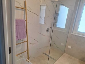 A glass-enclosed shower with a marble floor, a wooden ladder, and a towel hanging on the wall. - WoW Sea view 2-bedroom in lovely Campomarino Lido at the beach! (Campomarino Lido)