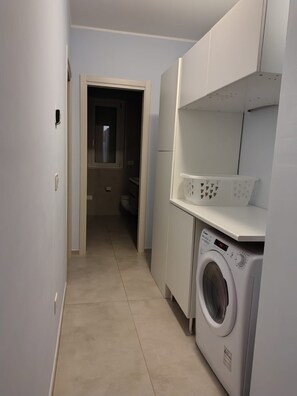 A laundry room with a washing machine, a drying rack, and a door leading to another room. - WoW Sea view 2-bedroom in lovely Campomarino Lido at the beach! (Campomarino Lido)
