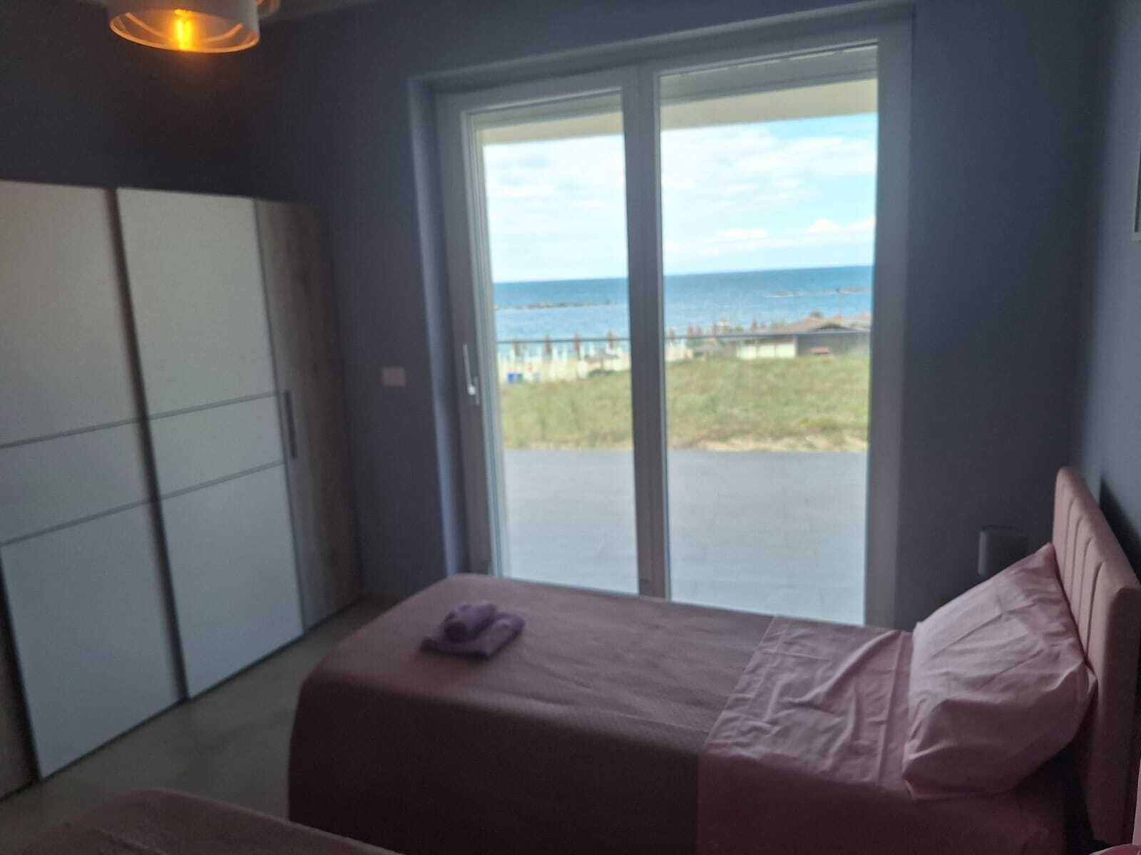 A bedroom with a bed, a wardrobe, and a view of the sea.