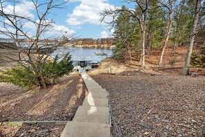 A concrete pathway leading to a dock by a lake, surrounded by trees and a clear sky. - Osage Beach - Main Channel Views & Cove Protection (Osage Beach)