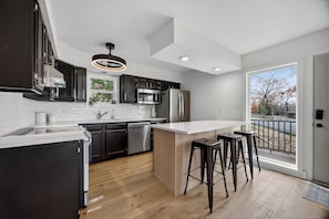 A modern kitchen with dark cabinets, stainless steel appliances, a white countertop, and a wooden floor. - Osage Beach - Main Channel Views & Cove Protection (Osage Beach)