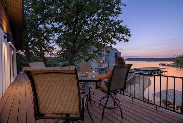 A deck with outdoor seating, a view of the water, and a building in the background. - Osage Beach - Main Channel Views & Cove Protection (Osage Beach)