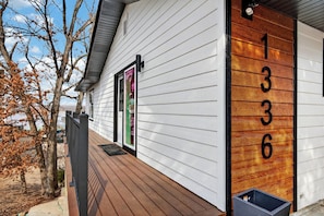 A house with a wooden number display, a porch, and a door with a green frame. - Osage Beach - Main Channel Views & Cove Protection (Osage Beach)