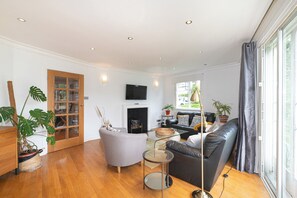 Ein modernes Wohnzimmer mit einer Couch, einem Sessel, einem Couchtisch, einem Kamin und einem Fernseher.