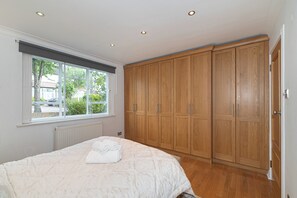 Ein Schlafzimmer mit einem großen Bett, einem Holzschrank und einem Fenster mit Blick nach draußen.