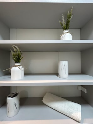 A minimalist shelf with three white ceramic containers, one with a plant, one with a plant and a rope, and one plain. - Fully Furnished Apartment in Manaus (Manaus)