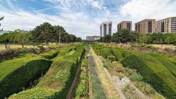 A landscaped garden with neatly trimmed hedges and a pathway. - Modern 2BR flat with Balcony, in East London - Pass the Keys (London)