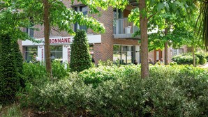 A building with balconies, a café named 'Café BONNAN É,' and dense greenery in front. - Modern 2BR flat with Balcony, in East London - Pass the Keys (London)