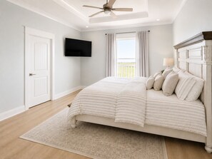 Un dormitorio con cama, ventilador de techo, televisor y ventana con cortinas.
