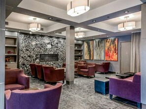Eine moderne Lobby mit Sitzbereichen, einem Kamin und Kunstwerken an den Wänden.