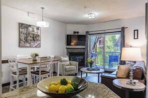 Ein modernes Wohnzimmer mit Essbereich, Kamin und Blick durch eine Glastür.