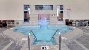 Una piscina interna con pavimento piastrellato, trampolino centrale e indicazione della profondità.