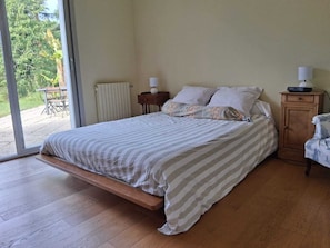A bedroom with a bed, bedside tables, a radiator, and a view of the outdoors. - Family home in the heart of the Nantes vineyards (Vertou)
