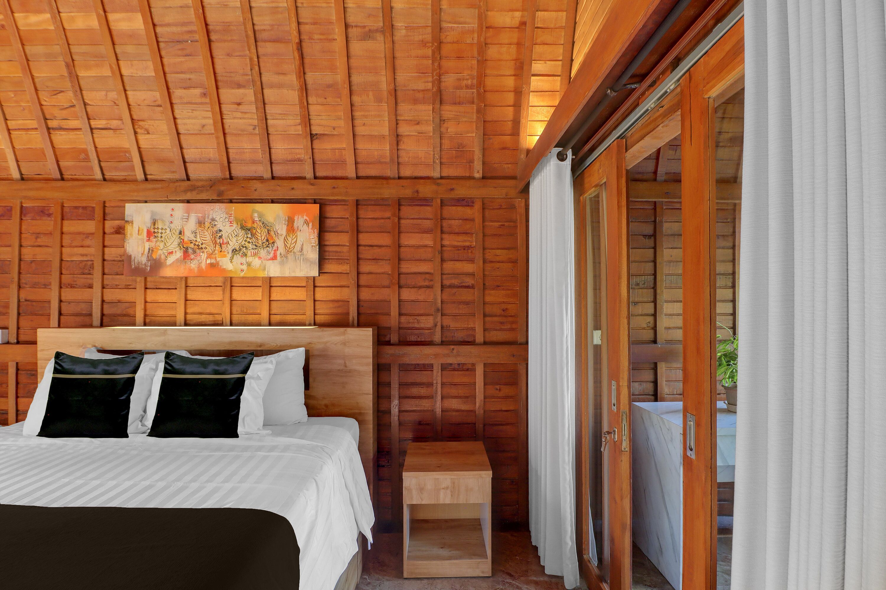 A wooden-paneled room with a bed, a small wooden nightstand, and a painting on the wall.