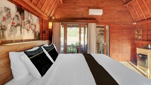 Eine Holzbalkendecke, ein Bett mit weißer und schwarzer Bettwäsche, ein Gemälde an der Wand und ein Blick durch eine Tür in einen Außenbereich.