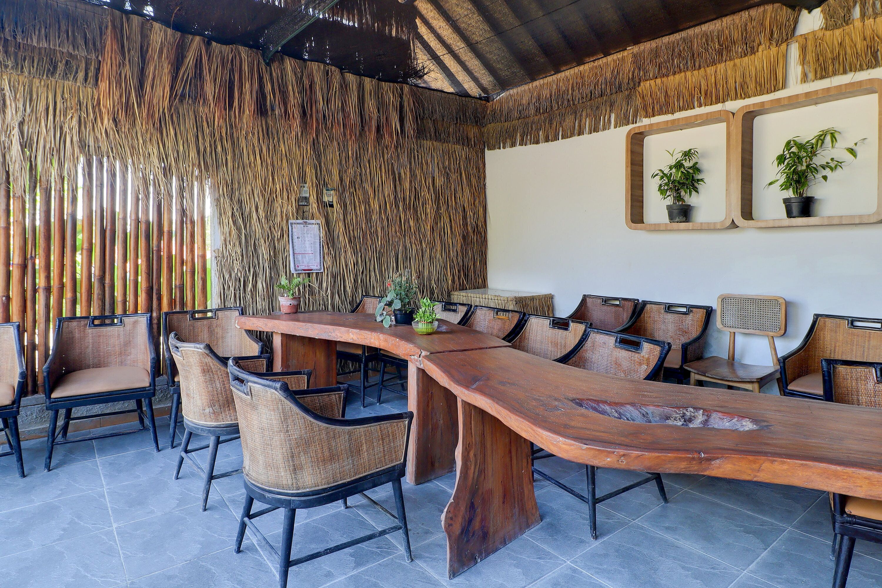 Un salón de conferencias con una larga mesa de madera, sillas de mimbre y plantas en macetas.