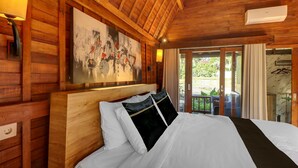 Ein Zimmer mit Holzwänden, einem Bett, einem Gemälde und einem Fenster mit Vorhängen.