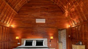 Una habitación con paneles de madera, una cama, dos lámparas de pared y una pequeña kitchenette.