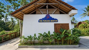 Ein Gebäude mit einem Schild, auf dem 'The Puriana Mantun' steht, und einem Holzdach.