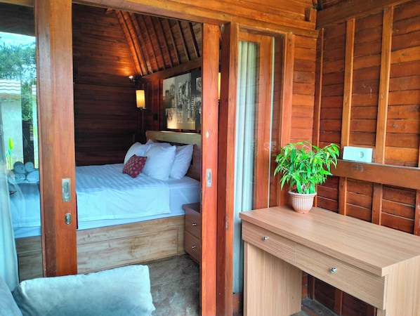 A wooden cabin room with a bed, bedside table, and a potted plant.