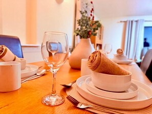 A dining table with a bowl of rolled bread, a wine glass, and plates. - Charming 4-bedroom Holiday Home in Chorley (Chorley)