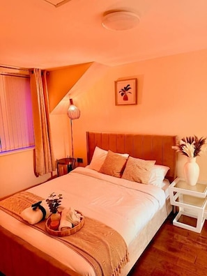 A hotel room with a bed, bedside table, lamp, and a wall-mounted picture.