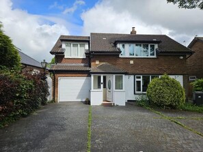 A two-story house with a garage, a front door, and a small porch. - Charming 4-bedroom Holiday Home in Chorley (Chorley)