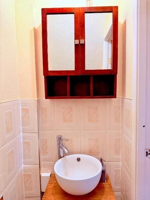 A bathroom with a wooden vanity, a white sink, and a mirror above it. - Charming 4-bedroom Holiday Home in Chorley (Chorley)