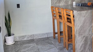 Una cucina con un piano di lavoro in marmo, sedie di legno e una pianta in vaso.