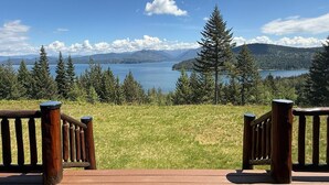 En terrass med träräcken med utsikt över en sjö och berg i bakgrunden.