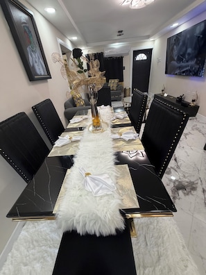 A dining room with a long table, black chairs, a white furry runner, and a vase with decorative elements.