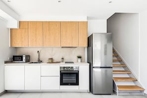 A modern kitchen with wooden cabinets, a stainless steel refrigerator, a built-in oven, and a microwave.