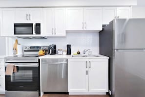 A modern kitchen with white cabinets, stainless steel appliances, and a herringbone tile backsplash. - Luxury Retreat Minutes from Niagara Falls & Casino (Niagara Falls)