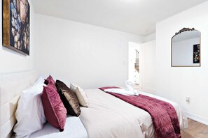A bedroom with a bed, pillows, a blanket, a mirror, and a painting on the wall. - Luxury Retreat Minutes from Niagara Falls & Casino (Niagara Falls)