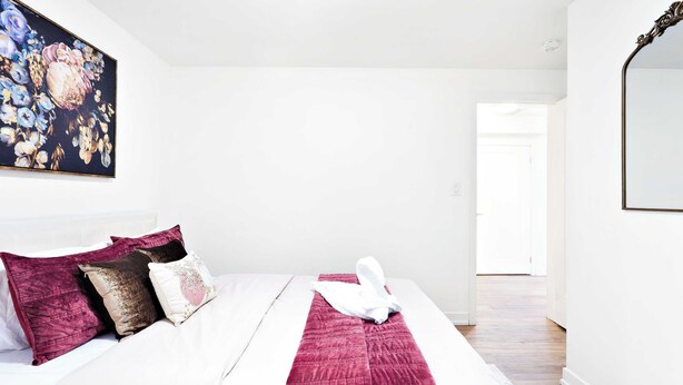 Un letto rifatto con un comofort bianco, una coperta rossa e un asciugamano bianco.