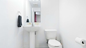 Un bagno con lavandino, wc e specchio bianchi.