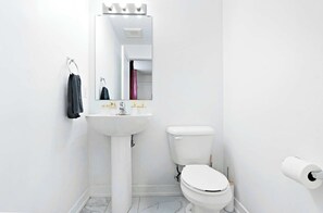 A bathroom with a white sink, toilet, and mirror. - Luxury Retreat Minutes from Niagara Falls & Casino (Niagara Falls)