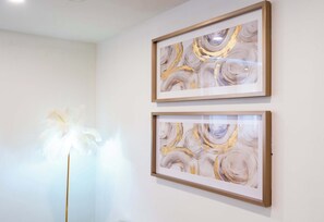 Two framed abstract paintings on a wall, a white feather-like object in the foreground, and a plain white wall. - Luxury Retreat Minutes from Niagara Falls & Casino (Niagara Falls)