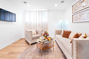 A modern living room with a sofa, armchair, coffee table, and artwork on the wall. - Luxury Retreat Minutes from Niagara Falls & Casino (Niagara Falls)