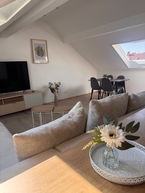 Un appartement moderne de style « loft », doté d’un coin repas, d’un téléviseur et d’une lucarne.